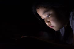 Kid with tablet sitting on bed and watching cartoons at night. stock photo Kid with tablet sitting on bed and watching cartoons at night. stock photo
