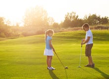 Kids At A Golf Field Holding Golf Clubs. Sunset Stock Photography