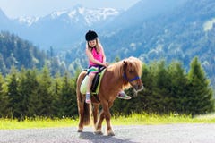 Kids riding pony. Child on horse in Alps mountains royalty free stock image Kids riding pony. Child on horse in Alps mountains royalty free stock image