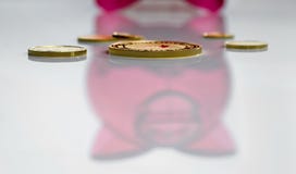 Kilka różne złociste monety na tle odbicie czerwony prosiątko bank zdjęcia royalty free Kilka różne złociste monety na tle odbicie czerwony prosiątko bank zdjęcia royalty free