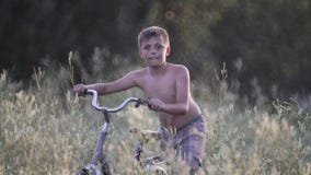 Kind auf Rest in einem Dorf mit einem Fahrrad in einem hohen Gras stock video Kind auf Rest in einem Dorf mit einem Fahrrad in einem hohen Gras stock video
