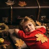 Kind liegt, Hände hinter Kopf legend und auf Bretterboden in den goldenen Blättern stillstehend Größte Rabatte für alle Herbstkle lizenzfreie stockfotografie Kind liegt, Hände hinter Kopf legend und auf Bretterboden in den goldenen Blättern stillstehend Größte Rabatte für alle Herbstkle lizenzfreie stockfotografie