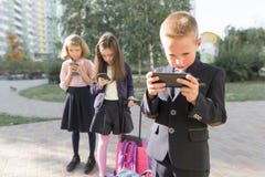 Kinder des grundlegenden Alters mit Smartphones, Rucks?cke, Hintergrund im Freien lizenzfreies stockbild Kinder des grundlegenden Alters mit Smartphones, Rucks?cke, Hintergrund im Freien lizenzfreies stockbild