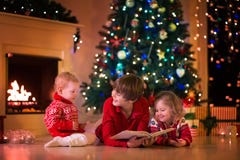 Kinder, die am Kamin auf Weihnachtsabend spielen lizenzfreies stockbild Kinder, die am Kamin auf Weihnachtsabend spielen lizenzfreies stockbild