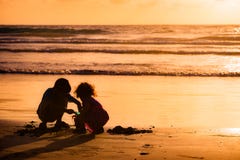Kinder, die mit Sand durch das Meer bei Sonnenuntergang in Tobago spielen lizenzfreies stockbild Kinder, die mit Sand durch das Meer bei Sonnenuntergang in Tobago spielen lizenzfreies stockbild