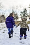 Kinder, die in Schneehändchenhalten gehen stockbild Kinder, die in Schneehändchenhalten gehen stockbild