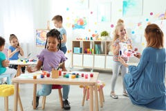 Kinder mit weiblichem Lehrer an malender Lektion stockfotos Kinder mit weiblichem Lehrer an malender Lektion stockfotos