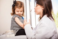 Kinderarzt, der einem Mädchen einen Schuss gibt stockfotografie Kinderarzt, der einem Mädchen einen Schuss gibt stockfotografie