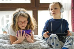 Kinderen die in bed met hun tabletten en telefoons spelen stock afbeelding Kinderen die in bed met hun tabletten en telefoons spelen stock afbeelding
