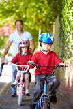 Kinderen die Fietsen berijden op Hun Manier aan School met Vader royalty-vrije stock foto's Kinderen die Fietsen berijden op Hun Manier aan School met Vader royalty-vrije stock foto's