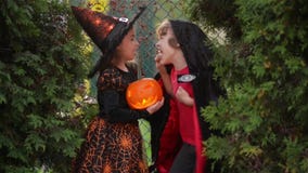 Kinderen die heksenkostuums met hoeden dragen die met pompoen met een brandende kaars in de herfstpark spelen op Halloween Jongen stock footage Kinderen die heksenkostuums met hoeden dragen die met pompoen met een brandende kaars in de herfstpark spelen op Halloween Jongen stock footage