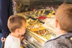 Kinderen die roomijs in een roomijswinkel bekijken stock afbeelding Kinderen die roomijs in een roomijswinkel bekijken stock afbeelding