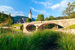 Kirche von SV Johannes der Täufer und eine Brücke durch den Bohinj See lizenzfreie stockfotografie Kirche von SV Johannes der Täufer und eine Brücke durch den Bohinj See lizenzfreie stockfotografie