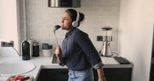 Woman listens music through headphones singing using ladle like microphone