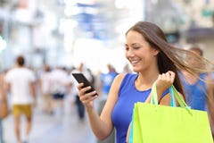 Klant die met smartphone in de straat winkelen Klant die met smartphone in de straat winkelen