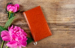 Klein boek en weelderige roze pioenen op houten lijst royalty-vrije stock fotografie Klein boek en weelderige roze pioenen op houten lijst royalty-vrije stock fotografie