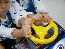 Kleine asiatische Babys, Geschwister, ein Lenkrad eines Arcade-Spiels teilend stockfoto Kleine asiatische Babys, Geschwister, ein Lenkrad eines Arcade-Spiels teilend stockfoto