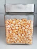 Kleine glaskruik met metaaldeksel met popcorn royalty-vrije stock fotografie Kleine glaskruik met metaaldeksel met popcorn royalty-vrije stock fotografie