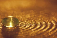Kleine glassteen op een plaat met gouden fonkelingen en bokeh royalty-vrije stock afbeeldingen Kleine glassteen op een plaat met gouden fonkelingen en bokeh royalty-vrije stock afbeeldingen