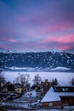 Kleine schneebedeckte Häuser in einer Stadt mit überraschendem Himmel und Bergen lizenzfreies stockbild Kleine schneebedeckte Häuser in einer Stadt mit überraschendem Himmel und Bergen lizenzfreies stockbild