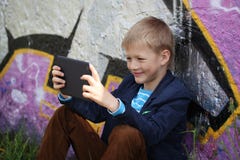 Kleiner Junge absorbiert in seine Tablette für die Erziehung und das Spielen stockfoto Kleiner Junge absorbiert in seine Tablette für die Erziehung und das Spielen stockfoto