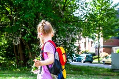 Kleines Mädchen, das mit Rucksack und Blumen geht stockfotografie Kleines Mädchen, das mit Rucksack und Blumen geht stockfotografie