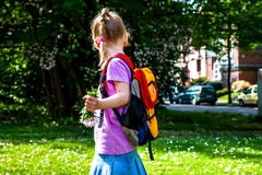 Kleines Mädchen, das mit Rucksack und Blumen geht lizenzfreie stockfotos Kleines Mädchen, das mit Rucksack und Blumen geht lizenzfreie stockfotos