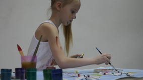 Kleines Schulm?dchen Netter Maler des kleinen M?dchens zeichnet auf dem Tisch und auf auf ihrer Kleidung Langsame Bewegung stock footage Kleines Schulm?dchen Netter Maler des kleinen M?dchens zeichnet auf dem Tisch und auf auf ihrer Kleidung Langsame Bewegung stock footage