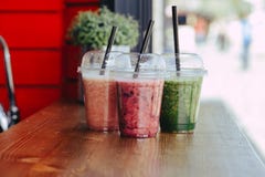 Kleurrijke Zoete smoothie in plastic koppen op houten lijst royalty-vrije stock afbeeldingen Kleurrijke Zoete smoothie in plastic koppen op houten lijst royalty-vrije stock afbeeldingen