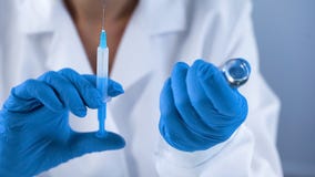 Kliniki pielęgniarka trzyma wtryskową strzykawkę w medycznych rękawiczkach, immunizacja program zdjęcia stock Kliniki pielęgniarka trzyma wtryskową strzykawkę w medycznych rękawiczkach, immunizacja program zdjęcia stock