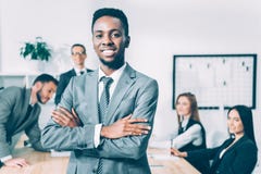 knappe Afrikaanse Amerikaanse manager met gekruiste wapens met vage multiculturele collega's royalty-vrije stock fotografie knappe Afrikaanse Amerikaanse manager met gekruiste wapens met vage multiculturele collega's royalty-vrije stock fotografie