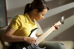 Kobieta bawić się w domu i trenuje z gitarą elektryczną obraz stock Kobieta bawić się w domu i trenuje z gitarą elektryczną obraz stock