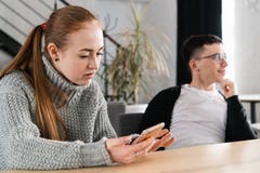 Kobieta czyta jej mężczyzna ` s cyganienia wiadomości na jego dzwoni obraz stock Kobieta czyta jej mężczyzna ` s cyganienia wiadomości na jego dzwoni obraz stock