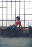 Kobieta opiera na ławce wybiera muzykę w loft gym obrazy royalty free Kobieta opiera na ławce wybiera muzykę w loft gym obrazy royalty free