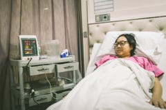 Kobieta podczas gdy kłamający w łóżku szpitalnym z tętno sprzętem medycznym obraz stock Kobieta podczas gdy kłamający w łóżku szpitalnym z tętno sprzętem medycznym obraz stock