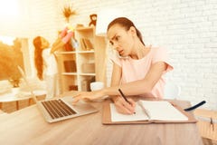 Kobieta siedzi przy stołem blisko działania i laptopu zdjęcie stock Kobieta siedzi przy stołem blisko działania i laptopu zdjęcie stock