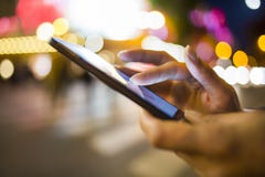 Kobieta używa jej telefon komórkowego w ulicie, nocy lekki environm