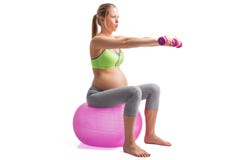 Kobieta w ciąży pracujący na medycyny piłce z dumbells w rękach out zdjęcia stock Kobieta w ciąży pracujący na medycyny piłce z dumbells w rękach out zdjęcia stock