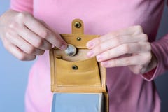 Kobieta w różowym pulowerze stawia monetę w otwartej kiesie Obrazy Stock Kobieta w różowym pulowerze stawia monetę w otwartej kiesie Obrazy Stock