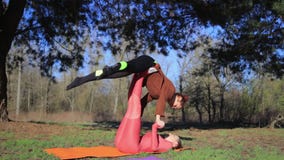 Kobiety dobierają się ćwiczy acroyoga w parku przy zmierzchem zbiory Kobiety dobierają się ćwiczy acroyoga w parku przy zmierzchem zbiory
