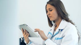 Kobiety pastylki doktorski używa komputer w medycznym biurze Kobiety pastylki doktorski używa komputer w medycznym biurze