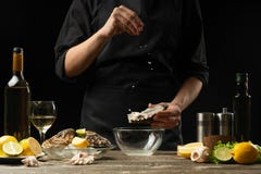Kock som saltar ostron med citronen på bakgrunden av torrt vin på en mörk bakgrund, horisontalfoto, meny, restaurang som är itali arkivbilder Kock som saltar ostron med citronen på bakgrunden av torrt vin på en mörk bakgrund, horisontalfoto, meny, restaurang som är itali arkivbilder
