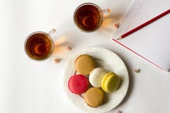 Kolorowi francuscy macaroons z dwa filiżankami herbata na białym mieszkaniu nieatutowym fotografia stock Kolorowi francuscy macaroons z dwa filiżankami herbata na białym mieszkaniu nieatutowym fotografia stock
