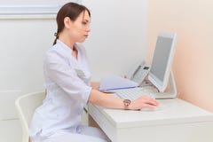 Koncentrerad doktor med rapporten som ser datorbildskärmen på skrivbordet i medicinskt kontor arkivbilder Koncentrerad doktor med rapporten som ser datorbildskärmen på skrivbordet i medicinskt kontor arkivbilder