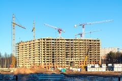 Konstruktion av en ny m?ng--v?ning byggnad som omges av skogar Konstruktionskranar mot den bl?a himlen fotografering för bildbyråer Konstruktion av en ny m?ng--v?ning byggnad som omges av skogar Konstruktionskranar mot den bl?a himlen fotografering för bildbyråer