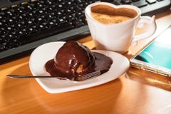 Kop van koffie en chocoladecake naast computer Royalty-vrije Stock Fotografie Kop van koffie en chocoladecake naast computer Royalty-vrije Stock Fotografie