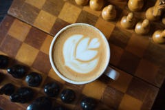 Kop van koffie en schaakbord door close-up op een houten achtergrond Soort van hierboven cappuccino stock afbeelding Kop van koffie en schaakbord door close-up op een houten achtergrond Soort van hierboven cappuccino stock afbeelding