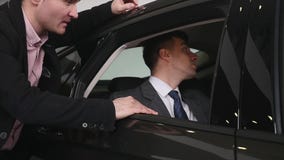 Koper die gesprek met autoverkoper hebben tijdens het inspecteren van de auto stock videobeelden Koper die gesprek met autoverkoper hebben tijdens het inspecteren van de auto stock videobeelden