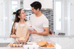 Koppla ihop danandebagerit, kakan i kökrum, den unga asiatiska mannen och kvinnan royaltyfri foto Koppla ihop danandebagerit, kakan i kökrum, den unga asiatiska mannen och kvinnan royaltyfri foto