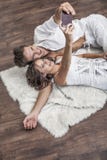 Koppla ihop mannen och kvinnan som tar selfies på golvet på mattan fotografering för bildbyråer Koppla ihop mannen och kvinnan som tar selfies på golvet på mattan fotografering för bildbyråer